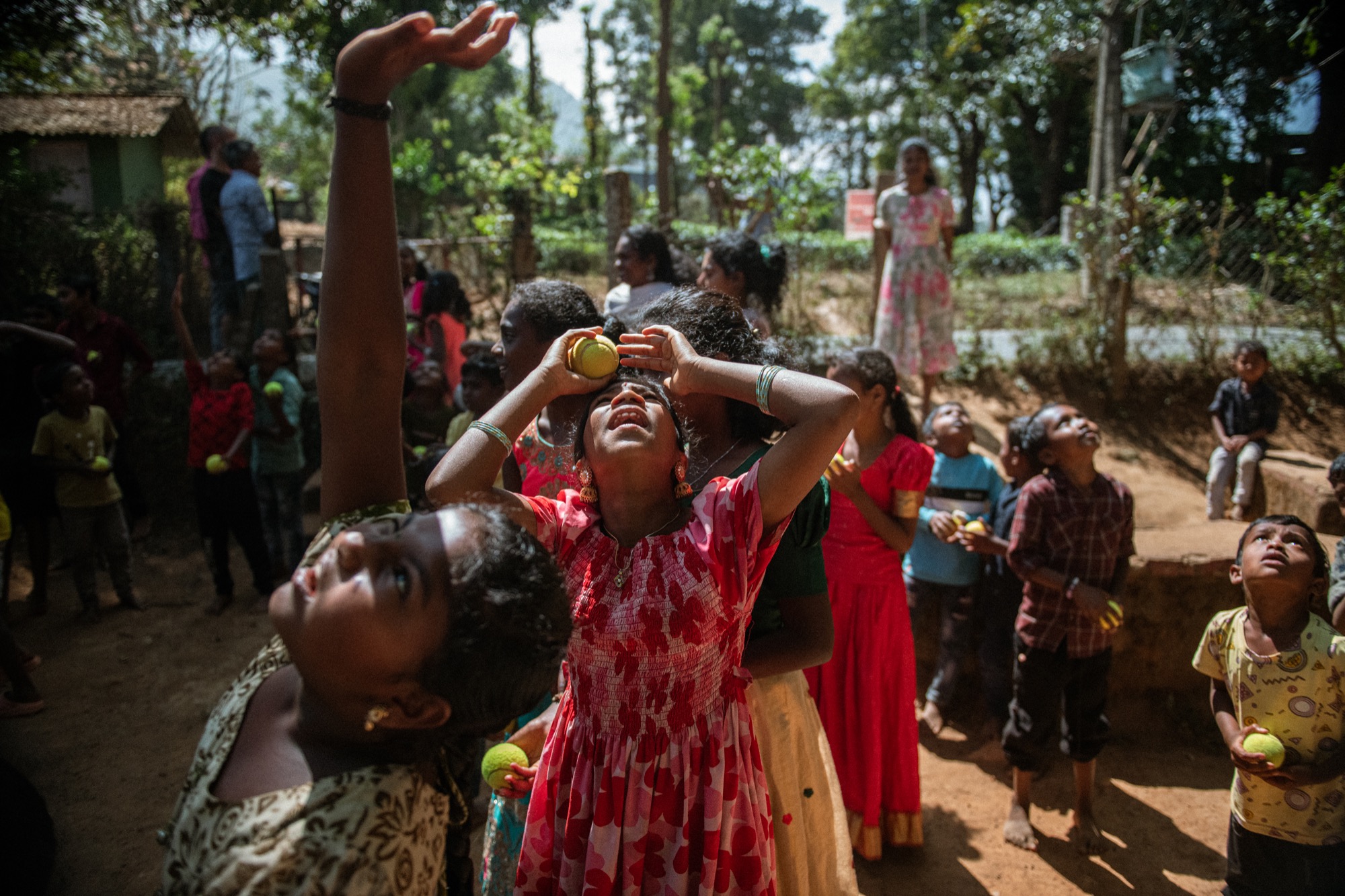Children in bright dresses playing a ball game outdoors