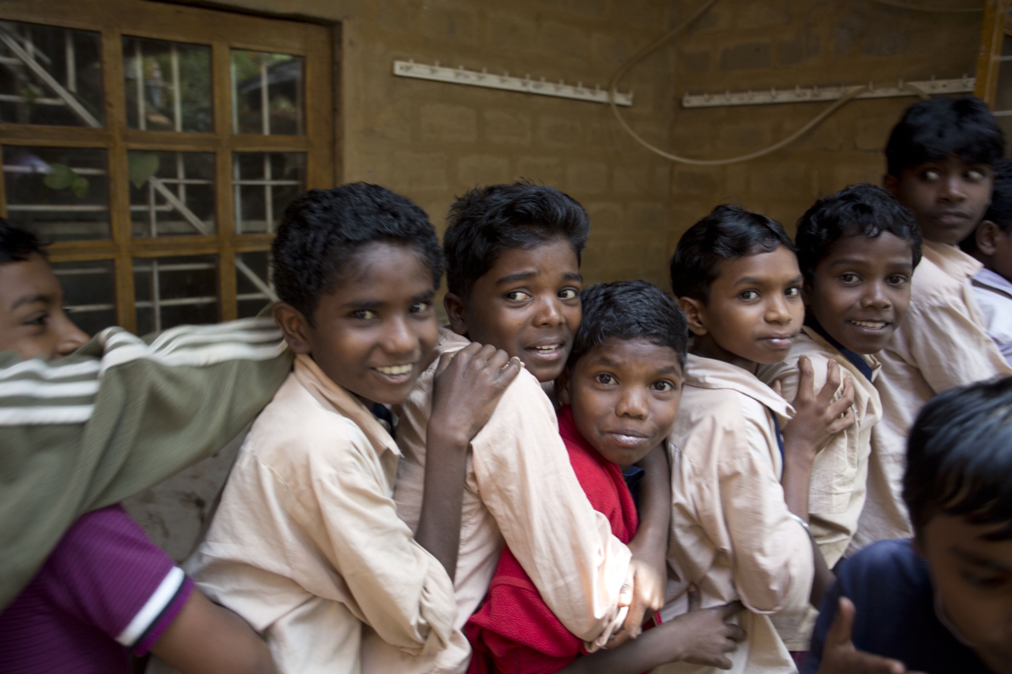 A group of Adivasi schoolboys smiling, arms around each other